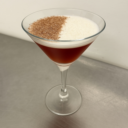 Martini glass with creamy layered cocktail.